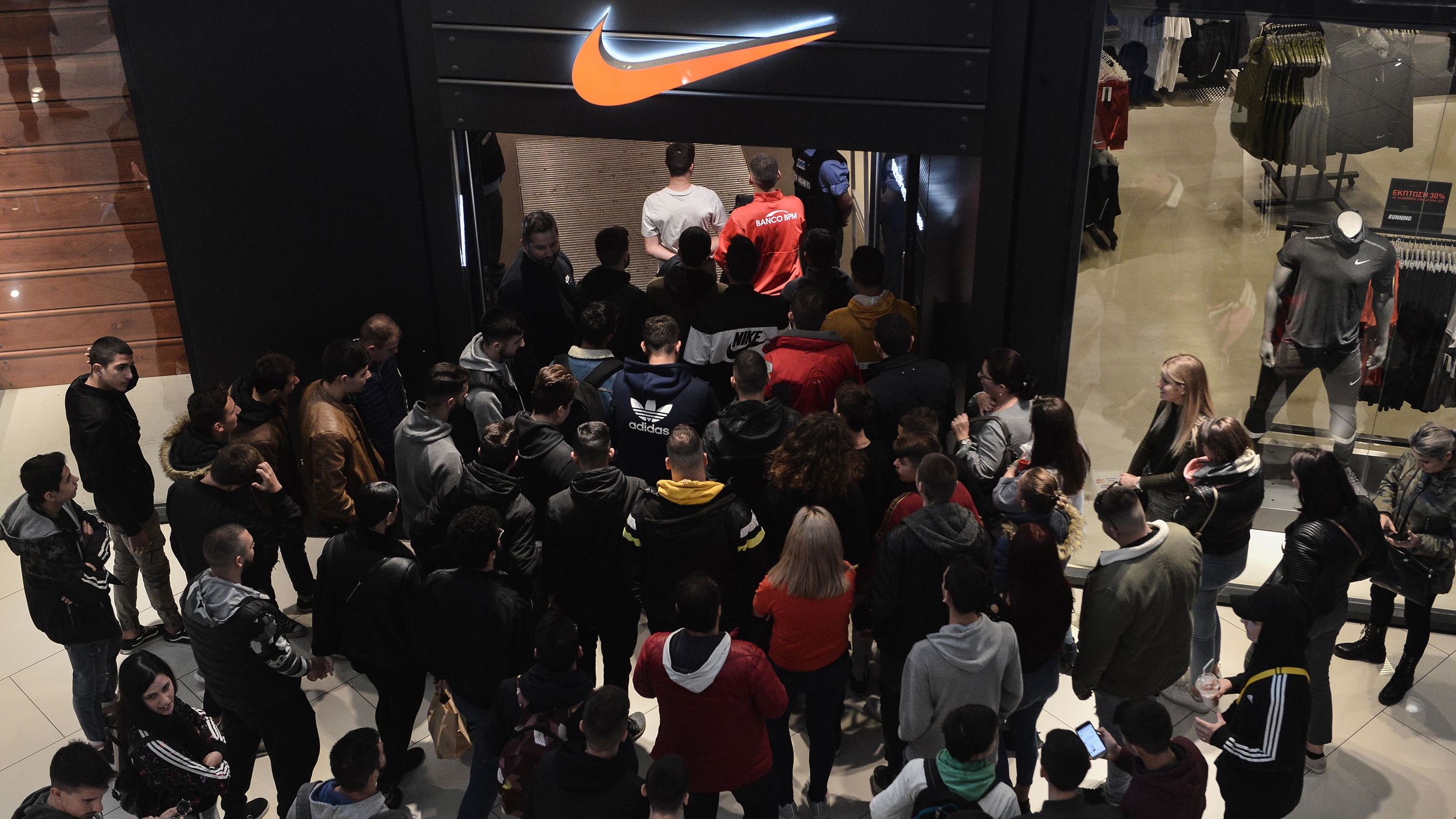 Customers wait at the entrance of a Nike store in Thessaloniki, Greece.