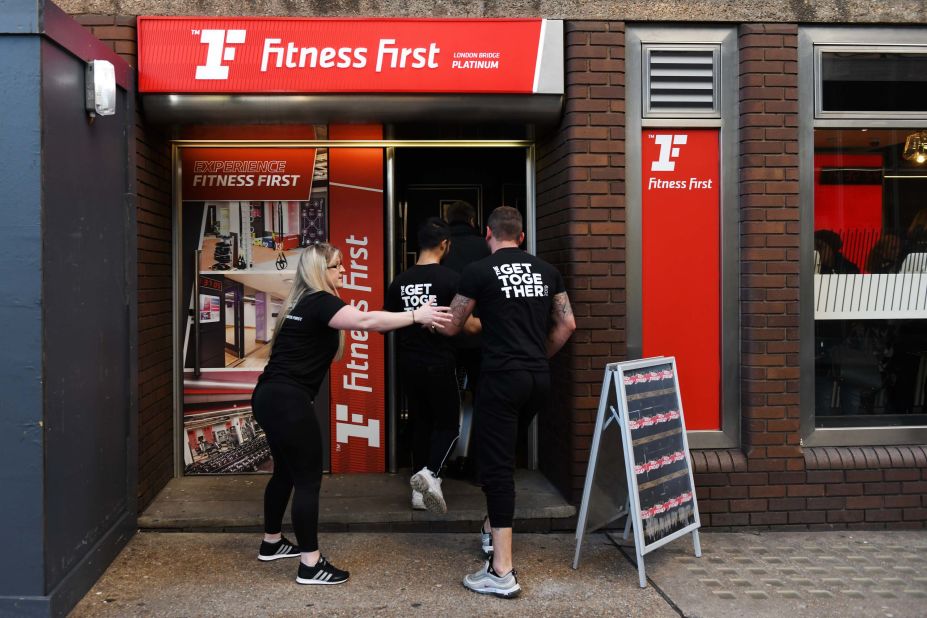 Staff members are ushered into a Fitness First gym after reports of shots being fired.