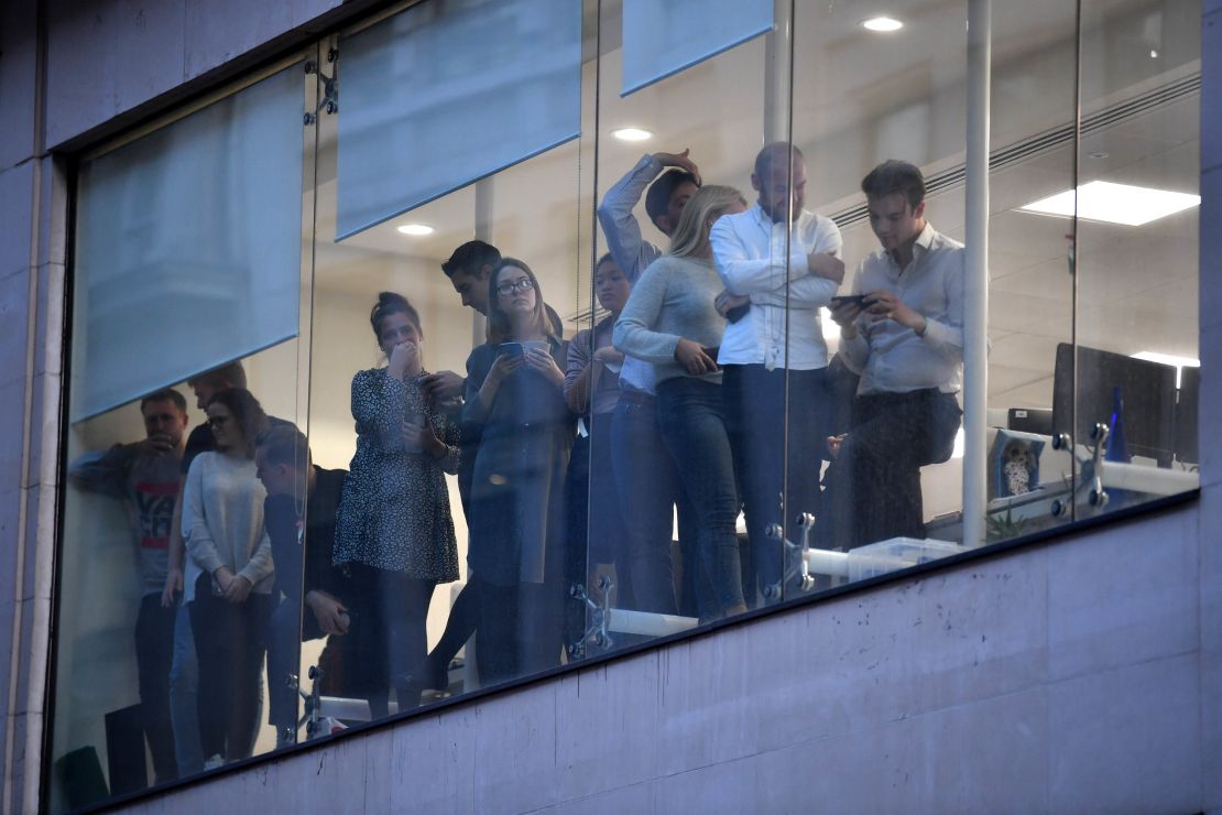 Office workers peer out of the windows of Leadenhall Market near London Bridge.