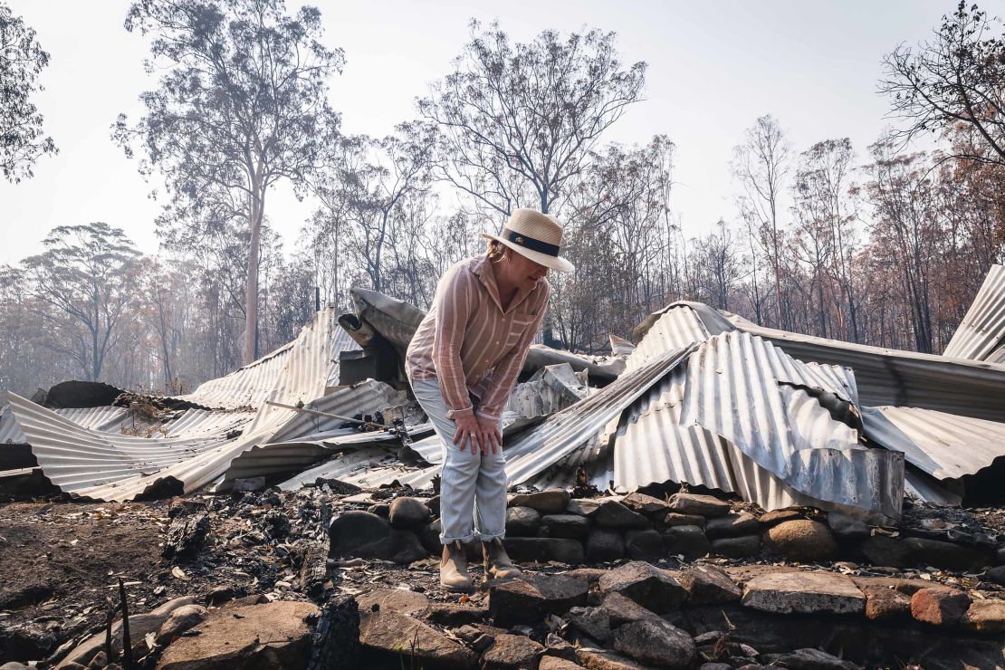 Bushfire survivor Melinda Plesman examines the remains of her destroyed property in Nymboida, NSW.