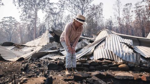Bushfire survivor Melinda Plesman examines the remains of her destroyed property in Nymboida, NSW.