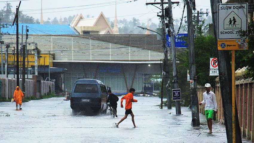 A child (C) wades through a flooded road following the passage of Typhoon Kammuri in Legaspi City, Albay province, south of Manila on December 3, 2019. - Typhoon Kammuri lashed the Philippines with fierce winds and heavy rain, as hundreds of thousands took refuge in shelters and the capital Manila prepared to shut down its international airport over safety concerns. (Photo by RAZVALE SAYAT / AFP) (Photo by RAZVALE SAYAT/AFP via Getty Images)
