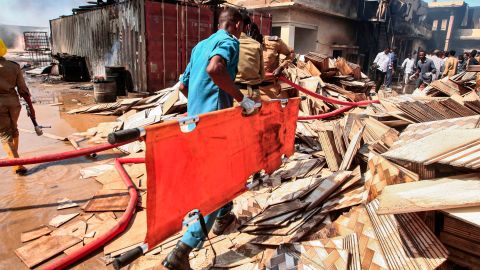 A Sudanese paramedic walks with a stretcher as others search for victims.