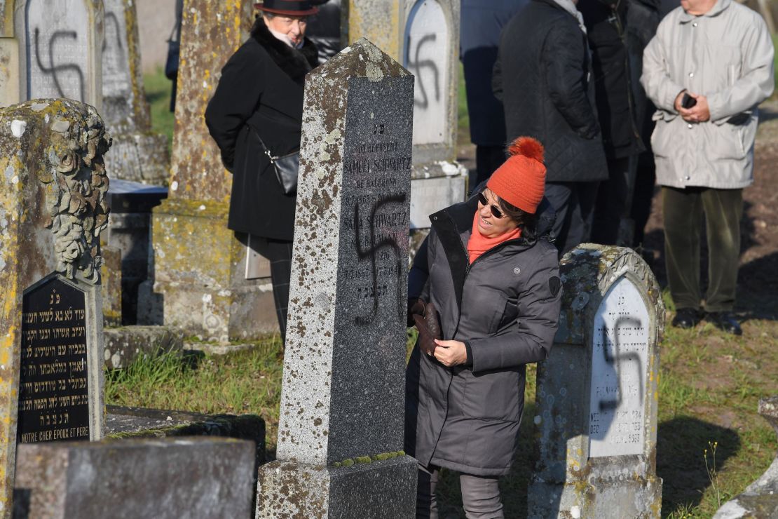 People look at graves at a Jewish cemetery near Strasbourg after they were desecrated with swastikas and anti-Semitic graffiti.