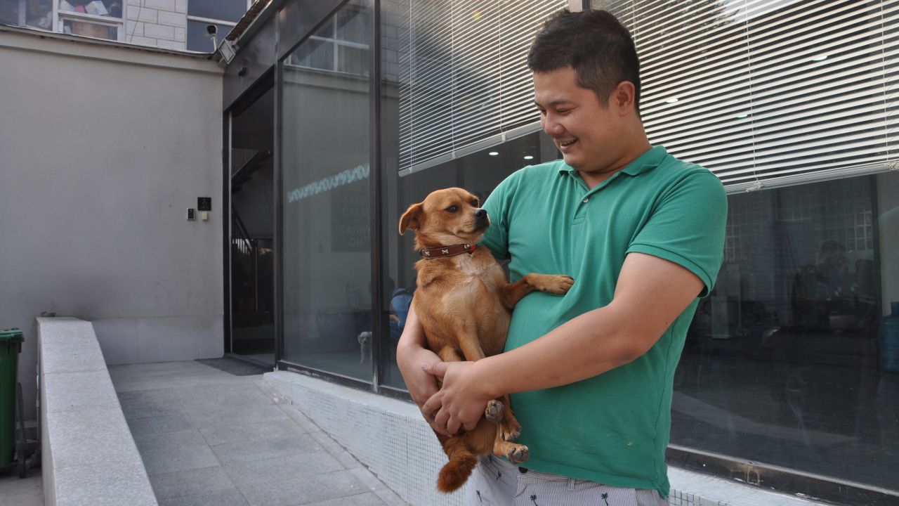 Joypets Funeral Home founder Li Chao holds one of his dogs at his workplace in Beijing in October.