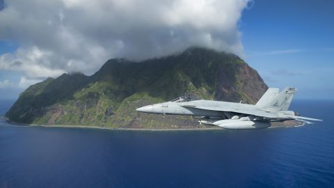 A US Navy F/A-18E Super Hornet jet flies past the island of North Iwo Jima in 2016.