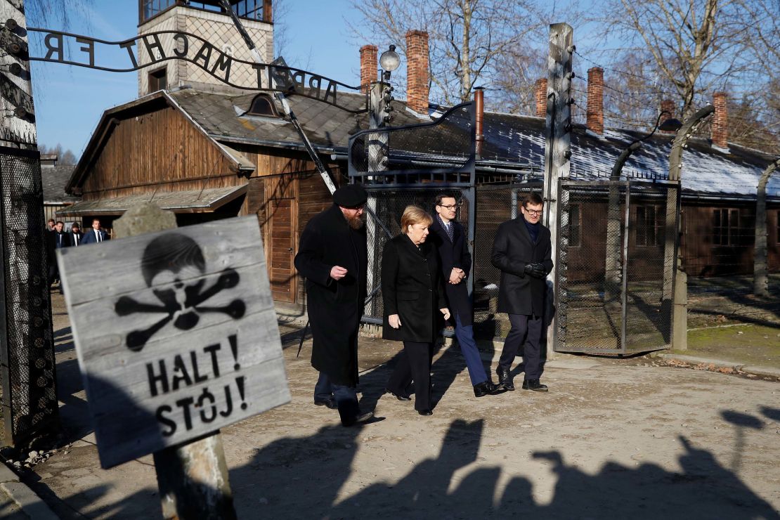 Merkel, Morawiecki and the Auschwitz museum director Piotr Cywinski walk past the "Arbeit Macht Frei" gate in the former Nazi death camp.
