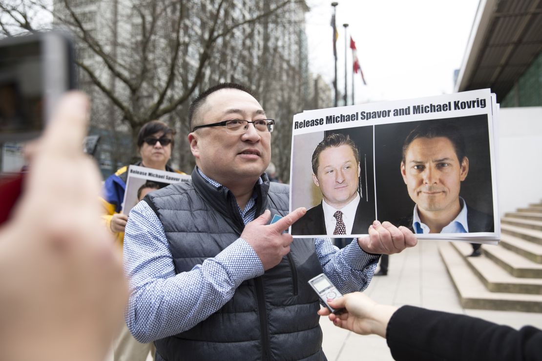 A protester holds photos of Canadians Michael Spavor and Michael Kovrig outside the British Columbia Supreme Court, in Vancouver, on March 6, 2019, as Huawei Chief Financial Officer Meng Wanzhou appeared in court.