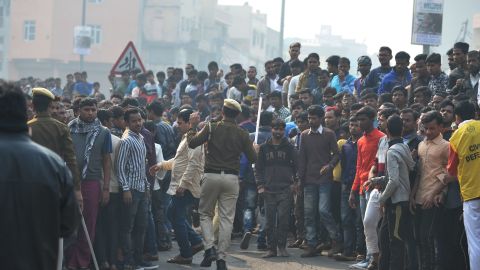 Police personnel try to clear a road as onlookers gather near the factory fire.