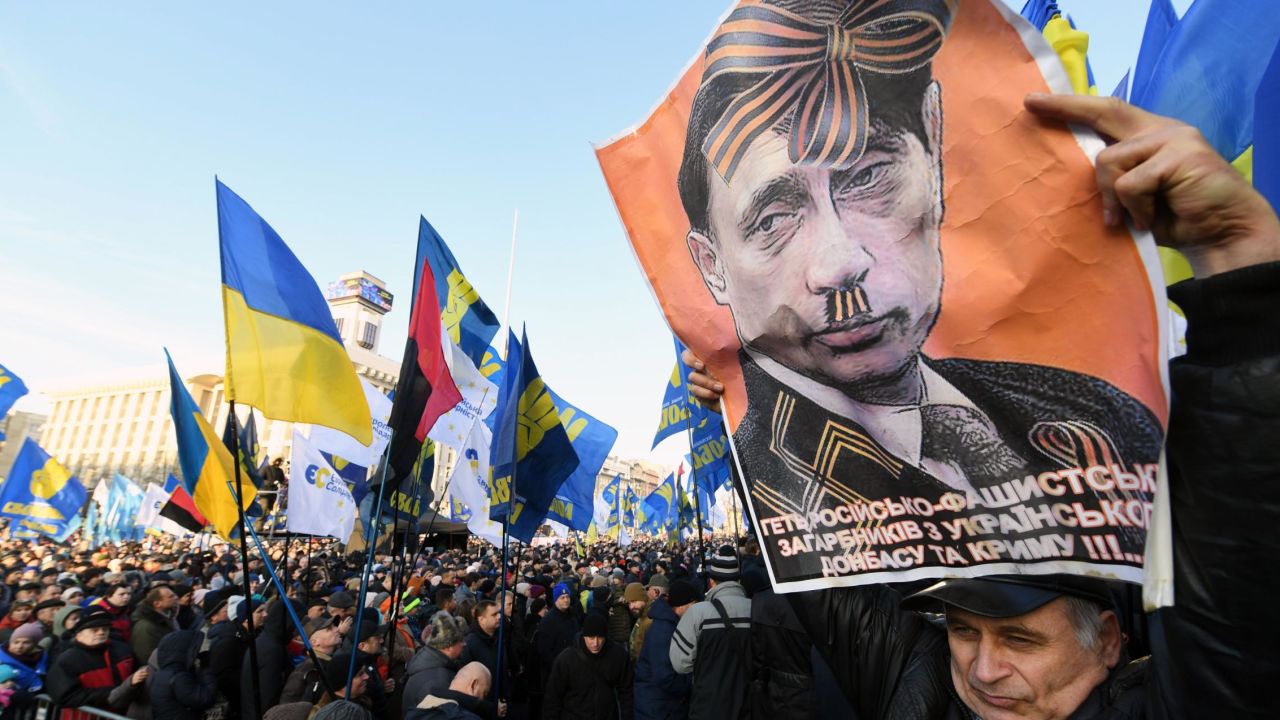 A man holds a poster of  Putin aloft at a protest in Kiev ahead of the Paris summit.