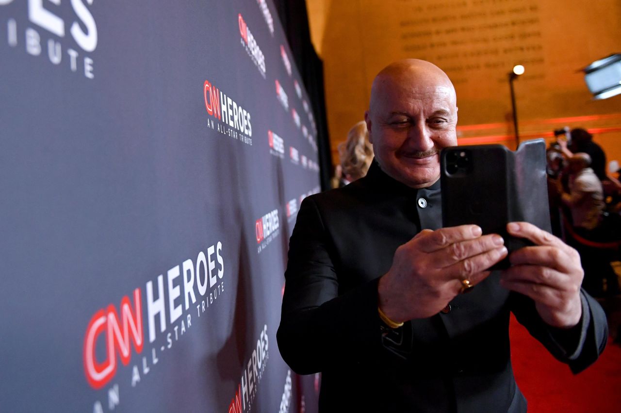 Actor Anupam Kher snaps a photo on his cell phone as he walks the red carpet.