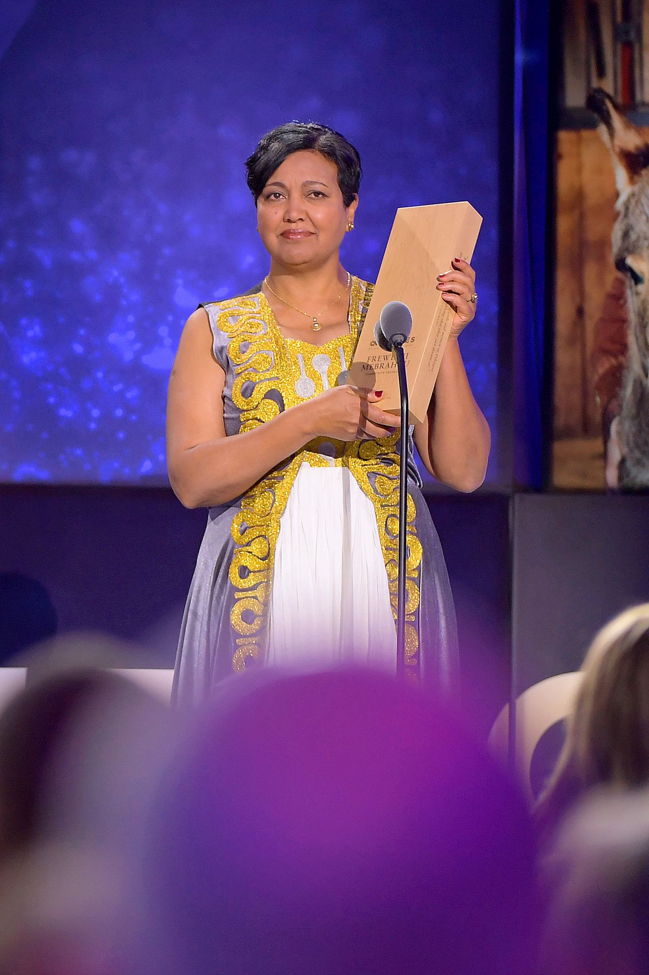 2019 Top 10 CNN Hero Freweini Mebrahtu holds up her award onstage. Mebrahtu teamed up with the nonprofit, Dignity Period, to end the stigma around the issue by speaking at schools and teaching girls and boys that menstruation is natural, not shameful.