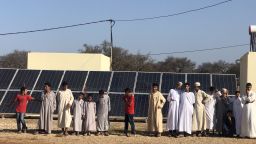 Villagers at Id Mjahidi in front of a bank of solar panels.