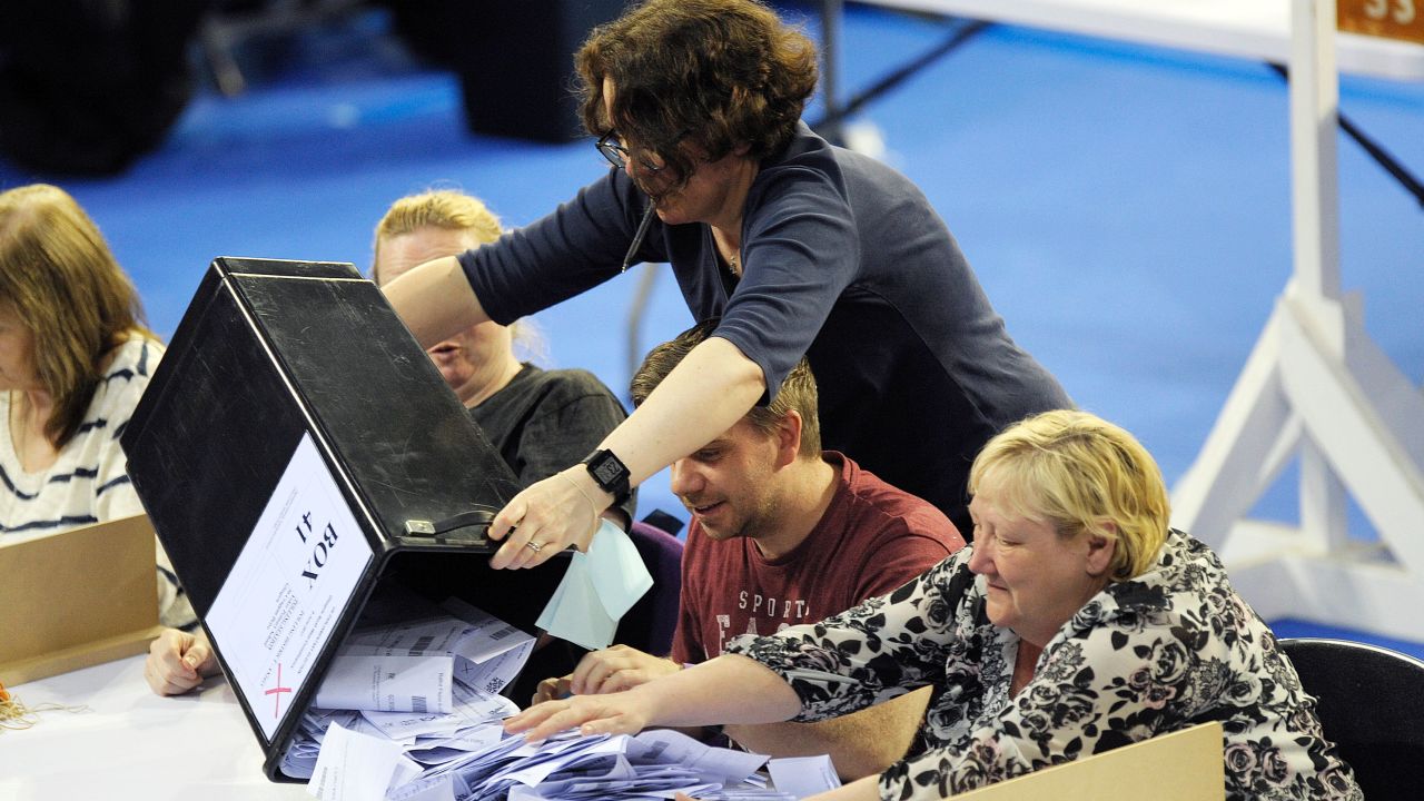 Staff members empty a ballot box at a counting centre in Glasgow, Scotland on June 8, 2017.