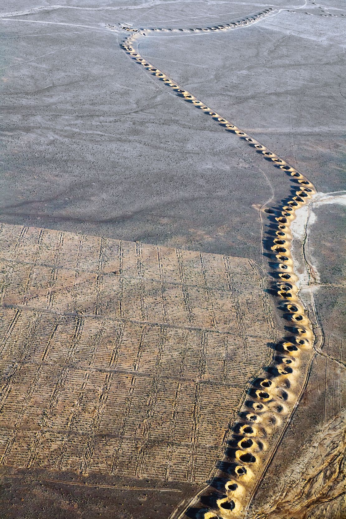 A line of evenly spaced spoil craters snakes along the surface of the desert from the high Elburz Mountains to the Plains of Iraq and is the only evidence of an invisible, subterranean man-made water stream called a qanat, first constructed by the Persians during the early years of the first millennium BCE.
