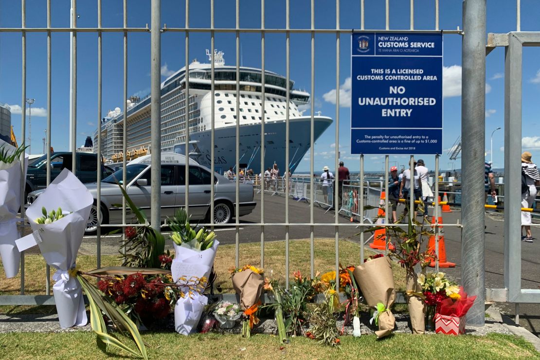Flowers are laid at a makeshift memorial seen in front of cruise ship Ovation of the Seas, in Tauranga, New Zealand, Tuesday, December 10, 2019. 