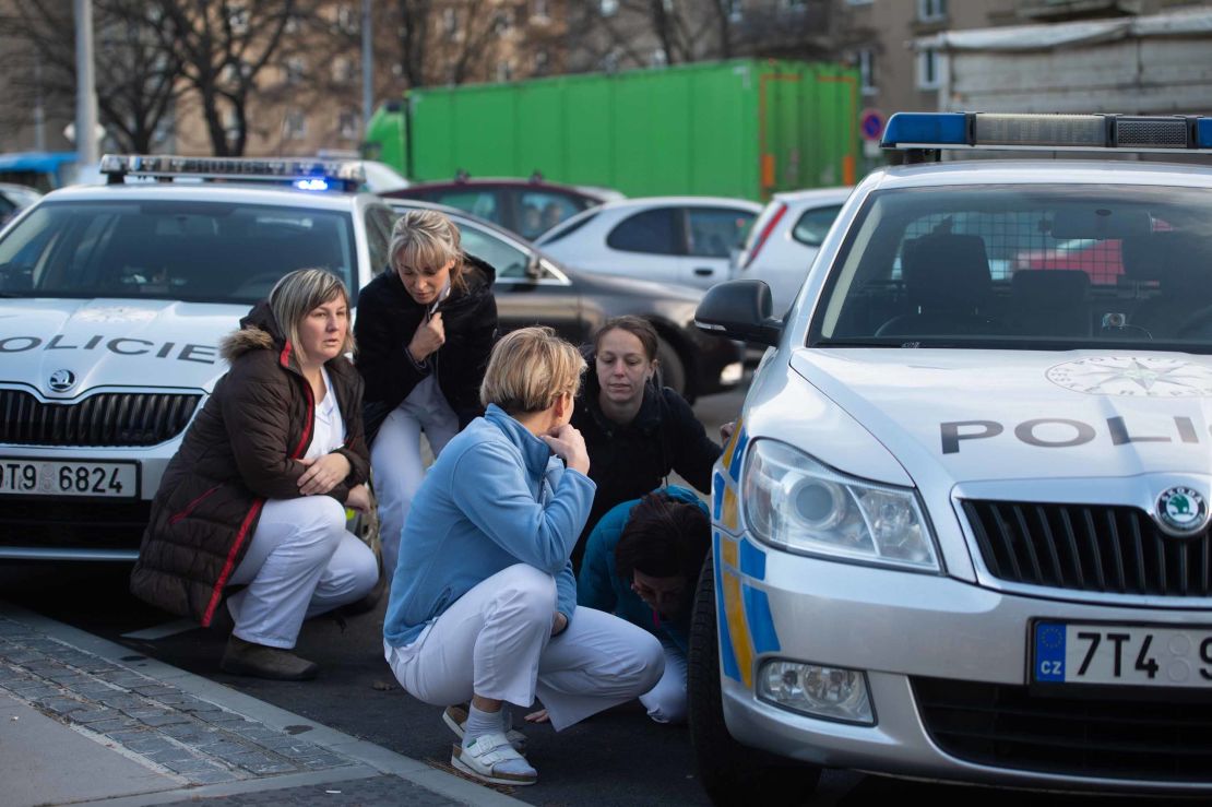 Staff hide behind police vehicles near the hospital in the eastern Czech city.
