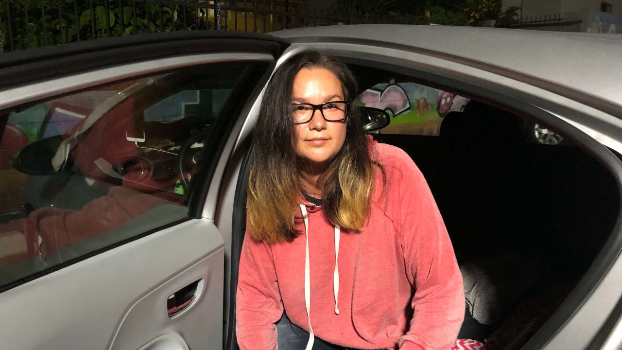 Lauren Kush poses beside the car where she sleeps.