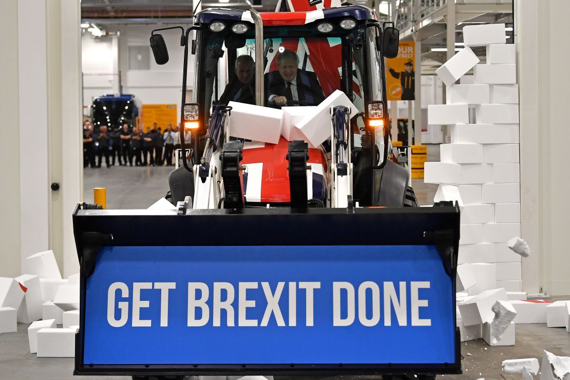 Boris Johnson drives a Union flag-themed JCB, with the words "Get Brexit Done" inside the digger bucket, during a general election campaign event in Uttoxeter, Staffordshire, on December 10, 2019. 