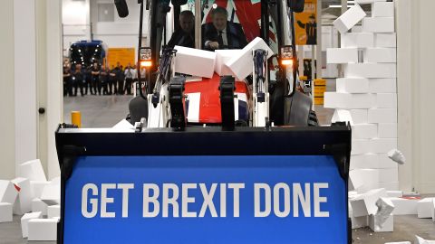 Boris Johnson drives a Union flag-themed JCB, with the words "Get Brexit Done" inside the digger bucket, during a general election campaign event in Uttoxeter, Staffordshire, on December 10, 2019. 