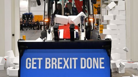 Boris Johnson drives a Union flag-themed JCB, with the words "Get Brexit Done" inside the digger bucket, during a general election campaign event in Uttoxeter, Staffordshire, on December 10, 2019.