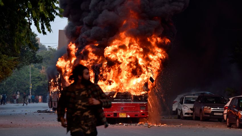 TOPSHOT - A man walks on a street as a bus is on fire following a demonstration against the Indian government's Citizenship Amendment Bill (CAB) in New Delhi on December 15, 2019. - Angry protesters in northeast India vowed on December 15 to keep demonstrating against a contentious citizenship law as the death toll from bloody clashes opposing the bill rose to six. (Photo by STR / AFP) (Photo by STR/AFP via Getty Images)