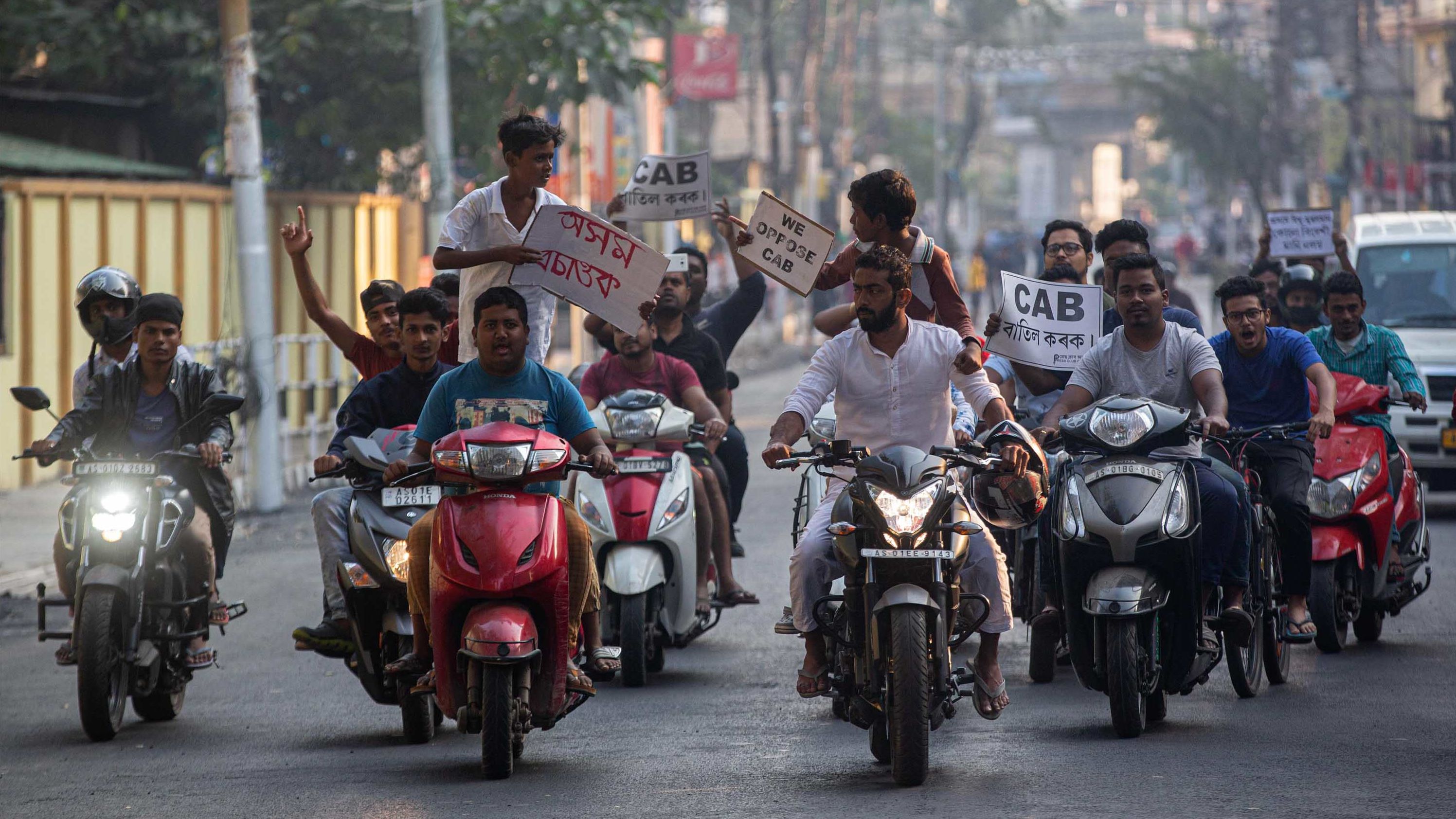 Protesters on motorbikes hold placards during a protest against the bill in Guwahati on Tuesday, December 10.