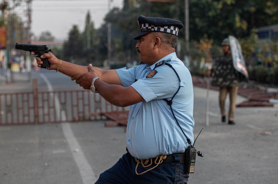 An Indian police officer aims his gun before firing toward protesters who threw stones in Guwahati on December 12.