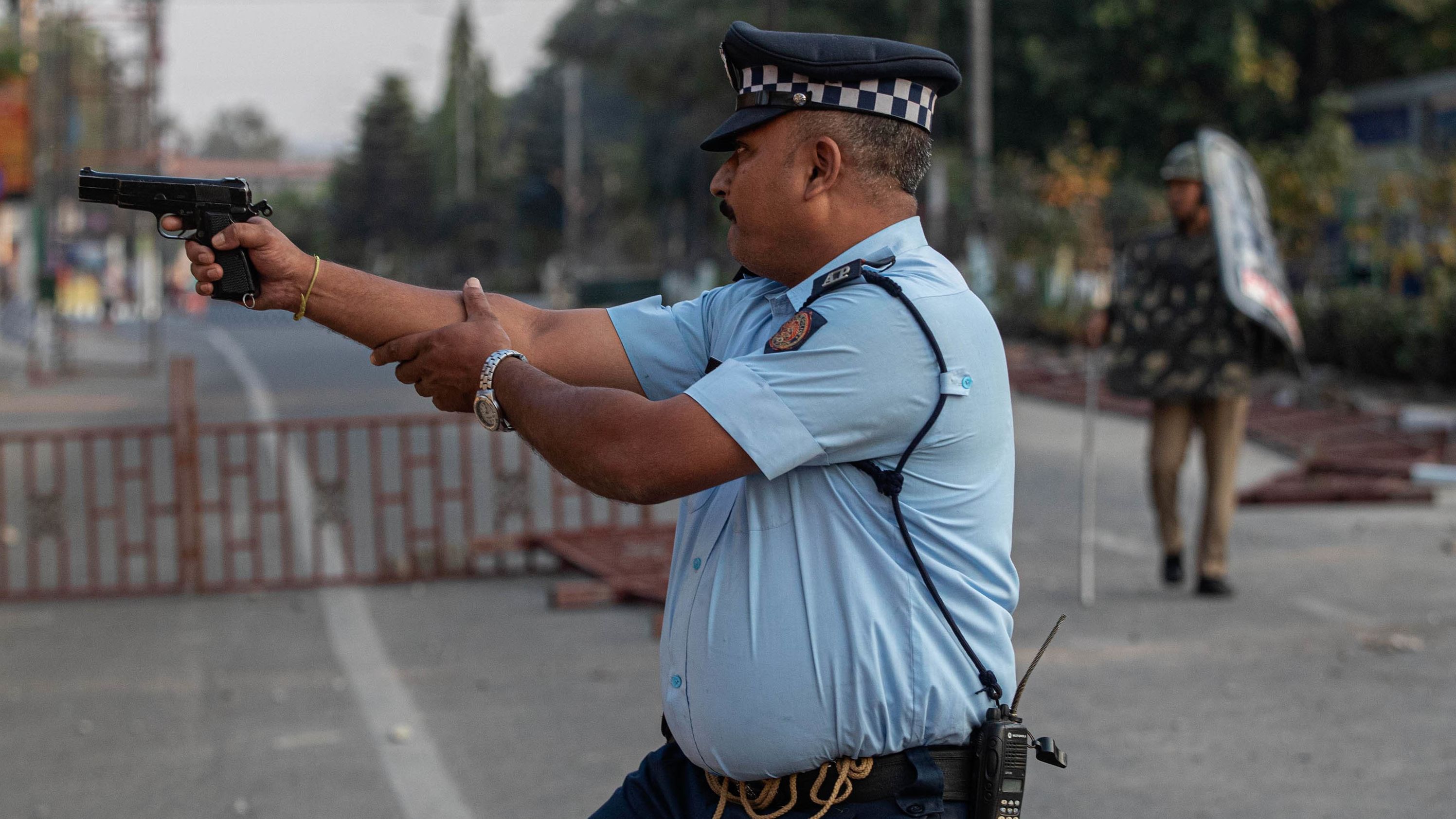 An Indian police officer aims his gun before firing toward protesters who threw stones in Guwahati on December 12.