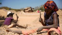 A child and a woman break rocks extracted from a cobalt mine at a copper quarry and cobalt pit in Lubumbashi on May 23, 2016.