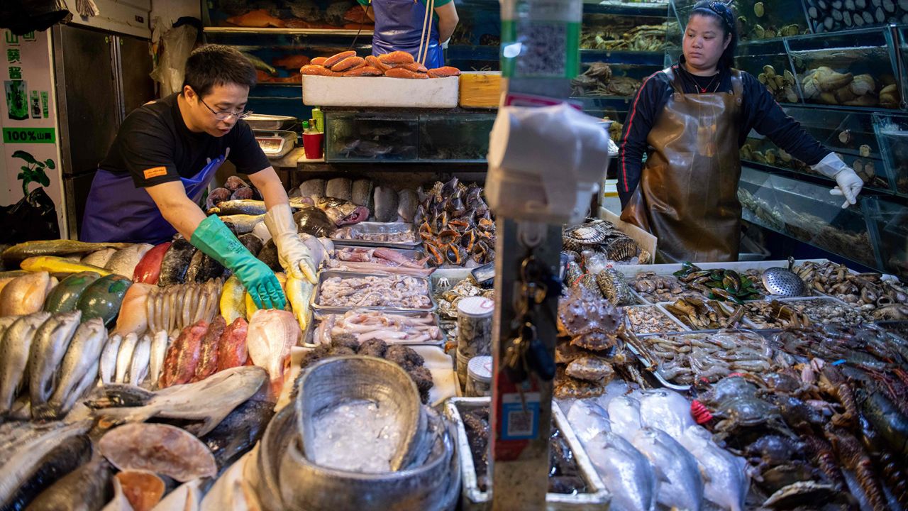 Workers prepare a stall filled with seafood at a market in Beijing on July 10, 2019.