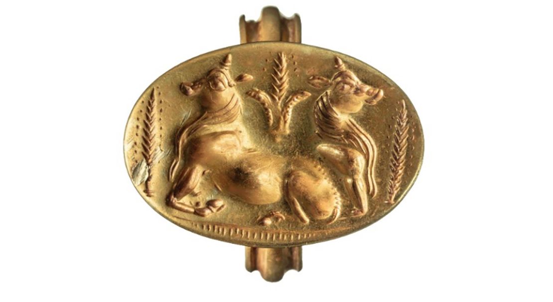 A gold ring depicts two bulls flanked by sheaves of grain.