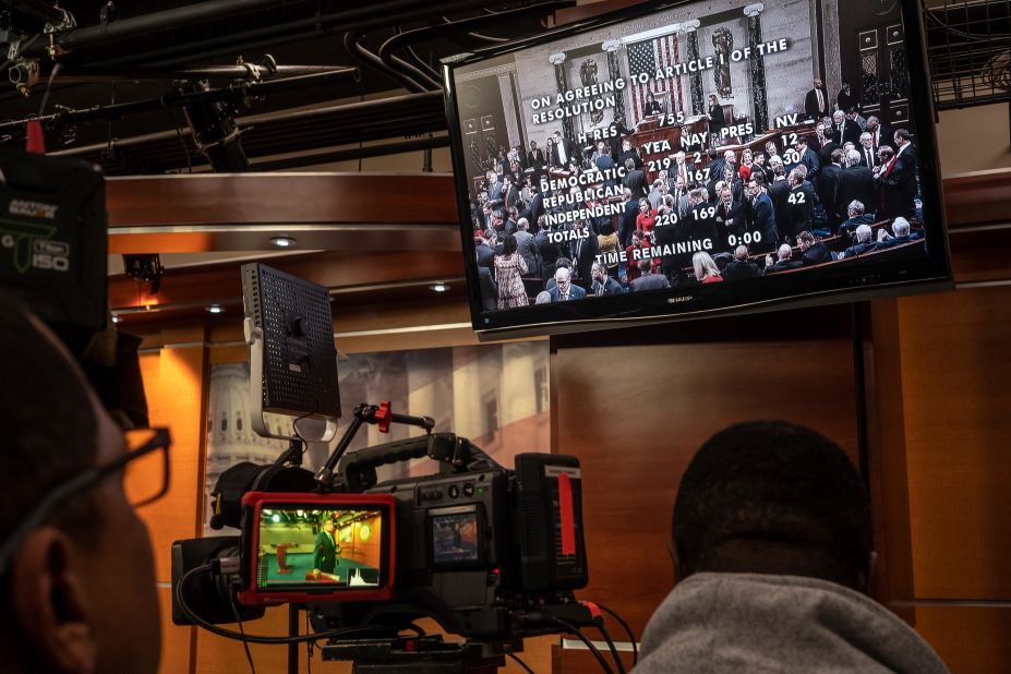 TV crews at the Capitol watch a live feed of the House votes.