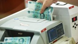 A Chinese bank employee counts new 50-yuan notes with a money counting machine at a bank counter in Hangzhou in China's eastern Zhejiang province on August 30, 2019, as the Peoples Bank of China issues the newest 2019 edition of the fifth series of the yuan notes.