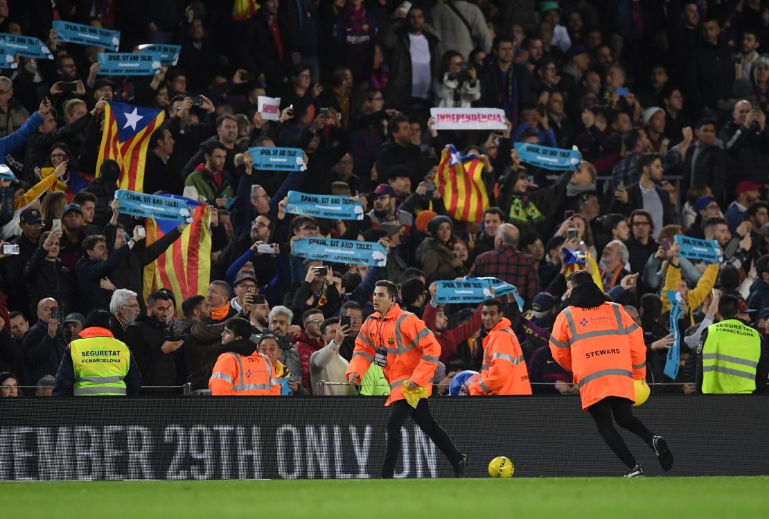 Yellow footballs are thrown onto the pitch in protest as fans hold "Spain, Sit and Talk" banners.