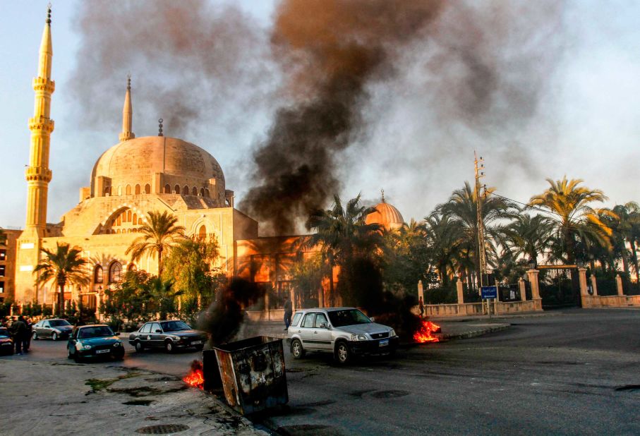 Cars navigate a flaming barricade set by anti-government protesters in the southern city of Sidon on November 19, ahead of a parliament session.