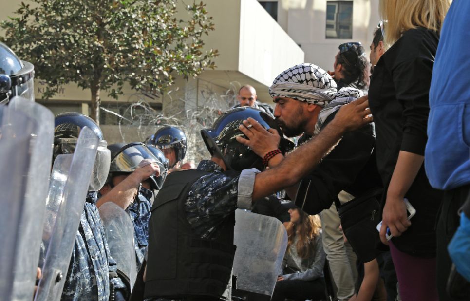 A Lebanese protester kisses the helmet of a riot policeman on November 19 near the parliament headquarters in Beirut.