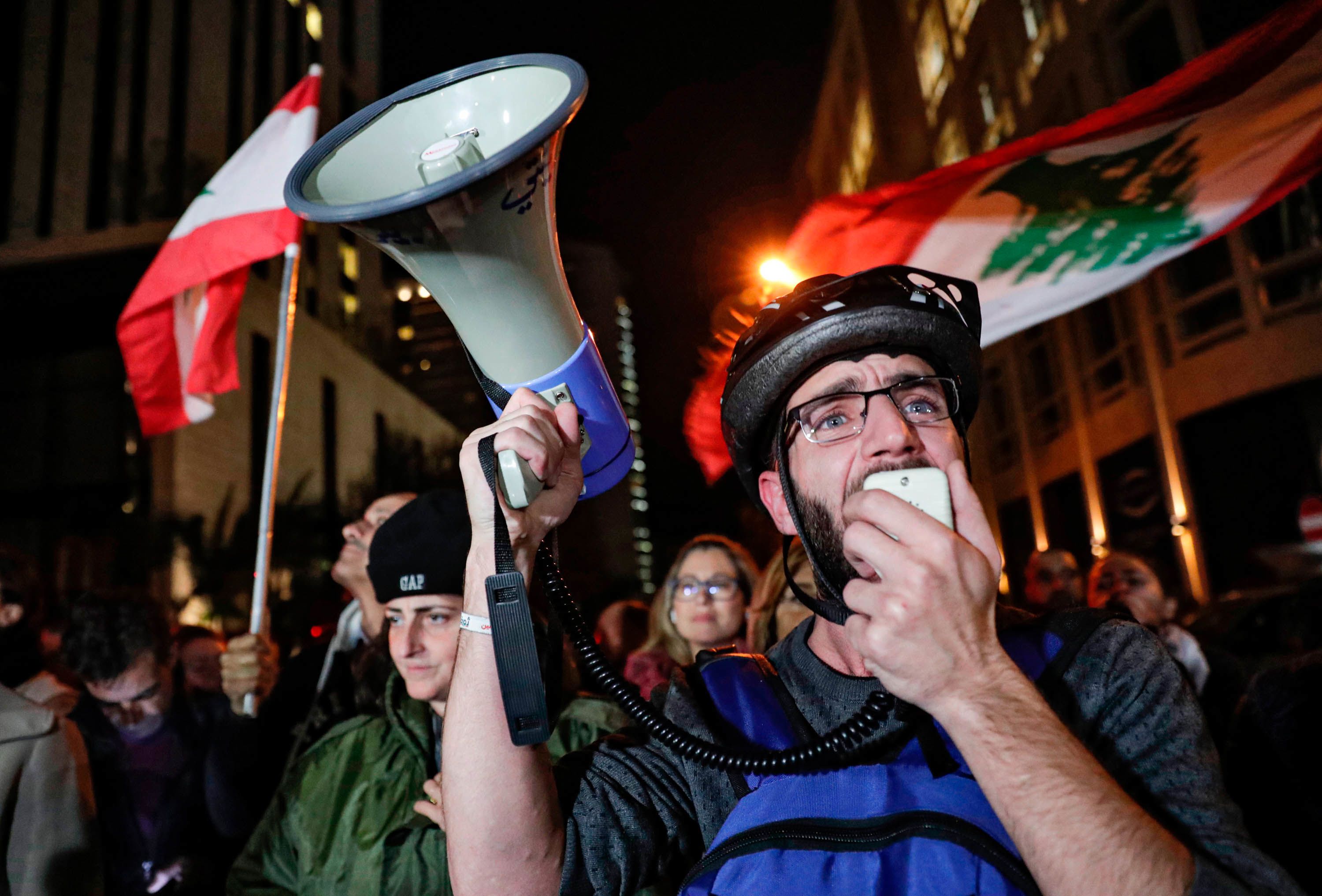 A Lebanese protester speaks into a megaphone on December 16 as demonstrators gather near the home of caretaker Prime Minister Saad Hariri in Beirut.