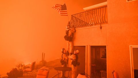 Firefighters <a href="https://www.cnn.com/2017/07/10/us/california-wildfires-firefighter-photo-trnd/index.html" target="_blank">remove an American flag</a> as a wildfire closes in on a home in Oroville, California, in July 2017. Raging wildfires forced thousands of people to evacuate their homes across the western United States. Scientists point to a number of conditions that have led to deadlier wildfires in recent years, all related to climate change.