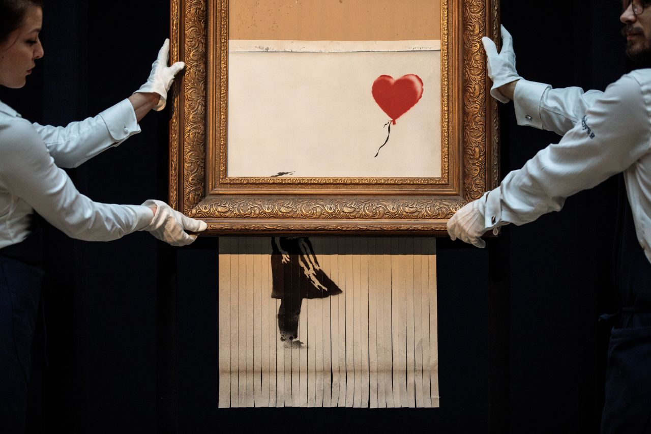 Employees from the Sotheby's auction house pose with Banksy's <a href="https://www.cnn.com/style/article/banksys-girl-with-balloon-renamed-love-is-in-bin/index.html" target="_blank">"Love is in the Bin"</a> in October 2018. The art was created a week earlier when Banksy's "Girl with Balloon" painting, which had just sold for $1.4 million, <a href="https://www.cnn.com/style/article/banksy-painting-self-destructs-auction-trnd/index.html" target="_blank">was damaged by a paper shredder</a> hidden inside the frame. After it was clear that this was the artist's intention, the buyer decided to keep it. 