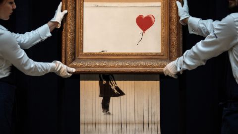 Employees from the Sotheby's auction house pose with Banksy's <a href="https://www.cnn.com/style/article/banksys-girl-with-balloon-renamed-love-is-in-bin/index.html" target="_blank">"Love is in the Bin"</a> in October 2018. The art was created a week earlier when Banksy's "Girl with Balloon" painting, which had just sold for $1.4 million, <a href="https://www.cnn.com/style/article/banksy-painting-self-destructs-auction-trnd/index.html" target="_blank">was damaged by a paper shredder</a> hidden inside the frame. After it was clear that this was the artist's intention, the buyer decided to keep it. 
