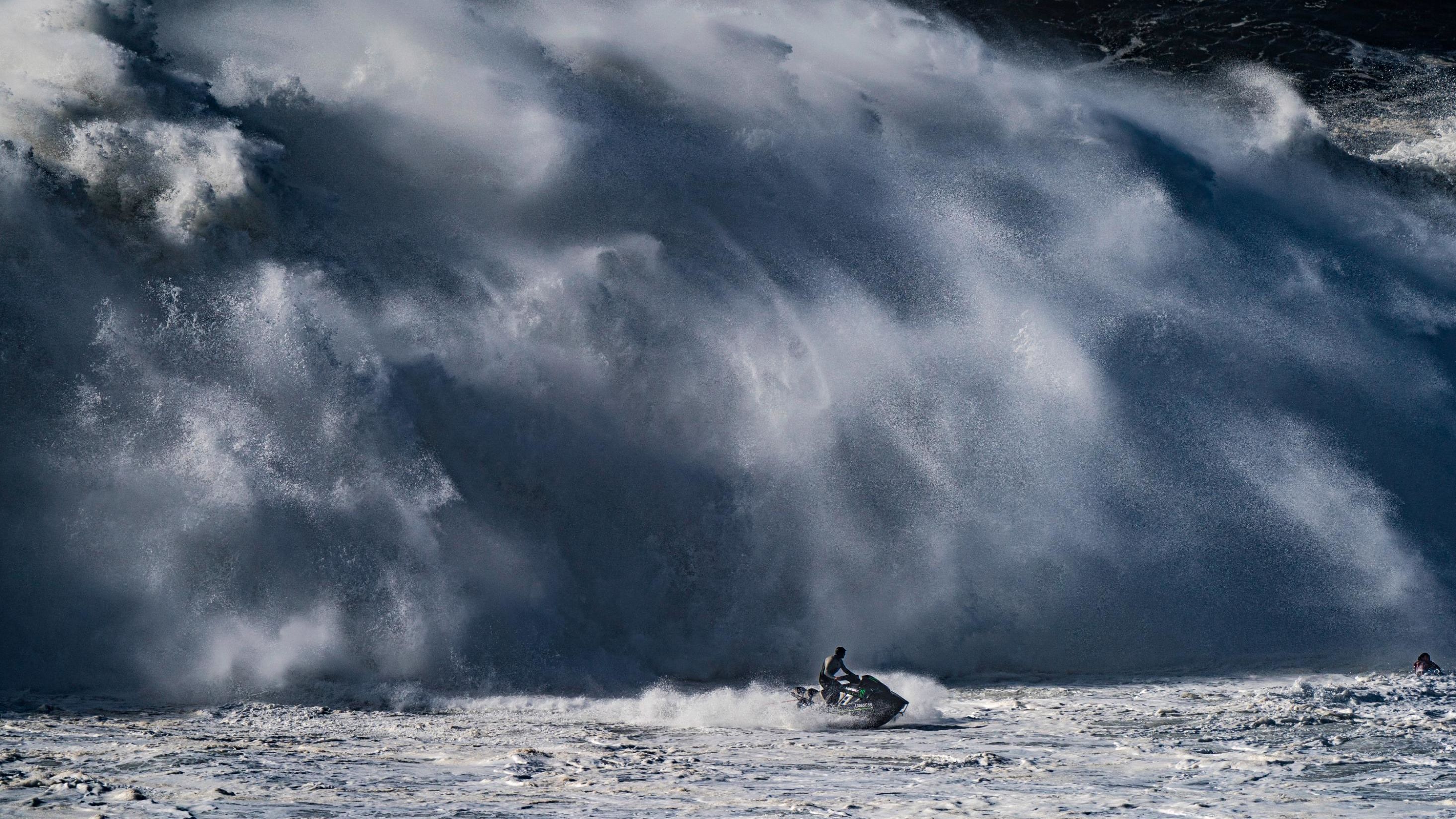 Big waves crash behind Nic von Rupp as he guides his jet ski to safety at Nazaré.