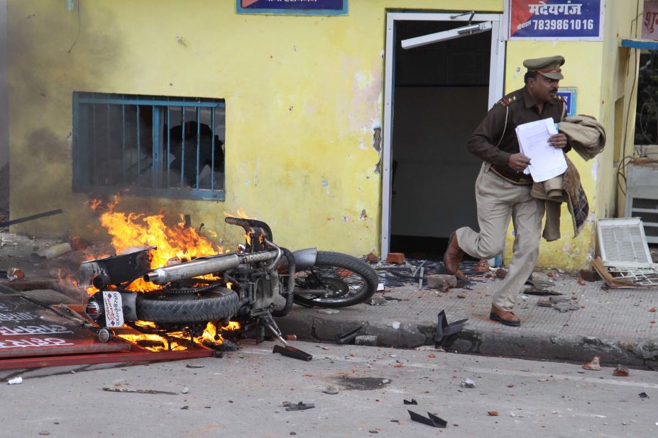 An officer flees a police station damaged by protesters during a demonstration in Lucknow on December 19.