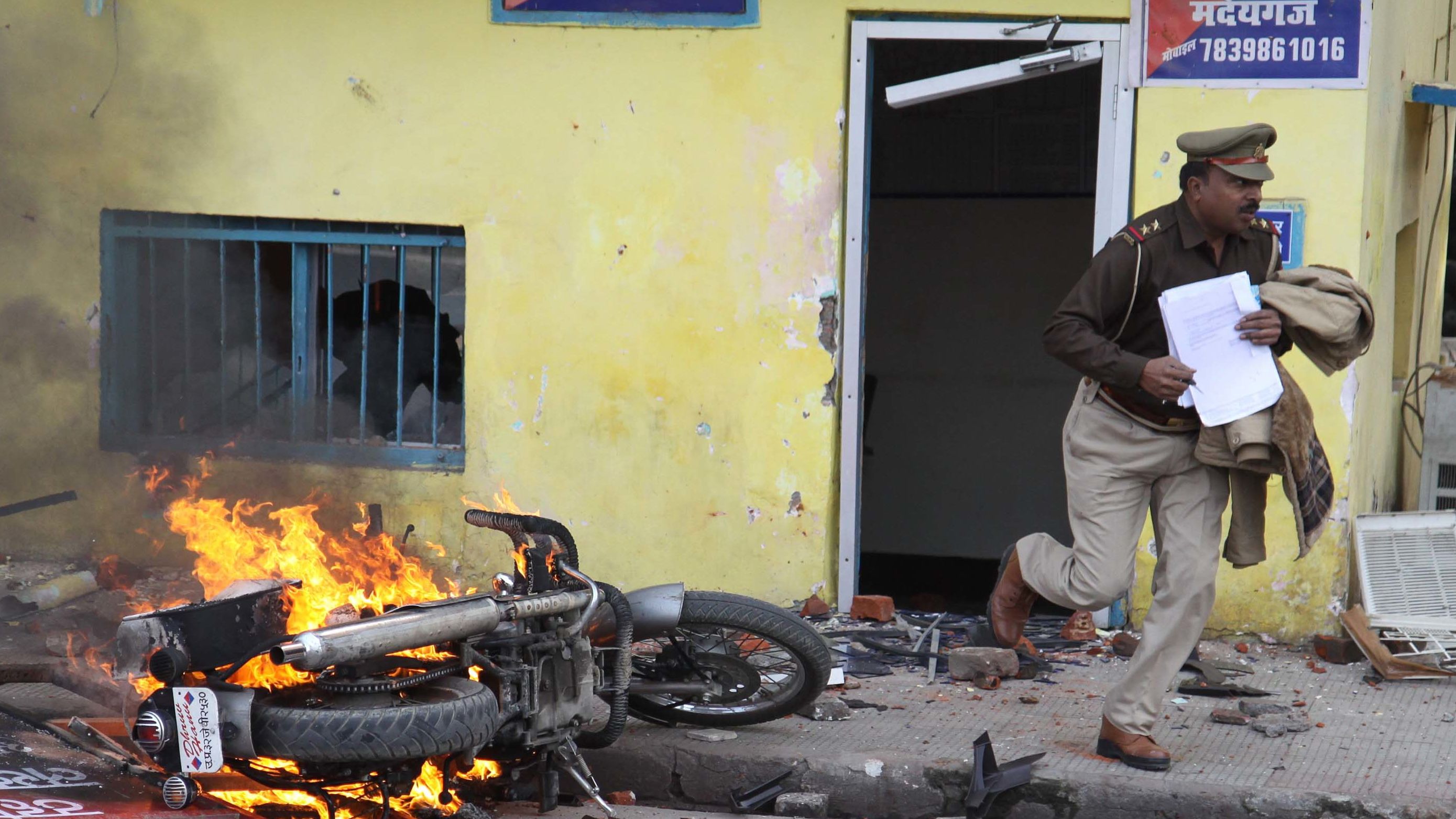 An officer flees a police station damaged by protesters during a demonstration in Lucknow on December 19.