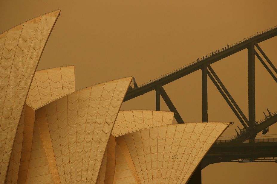 People join a guided climb of the Sydney Harbour Bridge as bushfire haze darkens the sky on December 6.