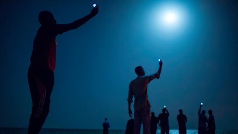 African migrants in Djibouti raise their phones to try to catch an inexpensive signal from neighboring Somalia in February 2013. Djibouti is a common stop-off point for African migrants seeking a better life in Europe and the Middle East.