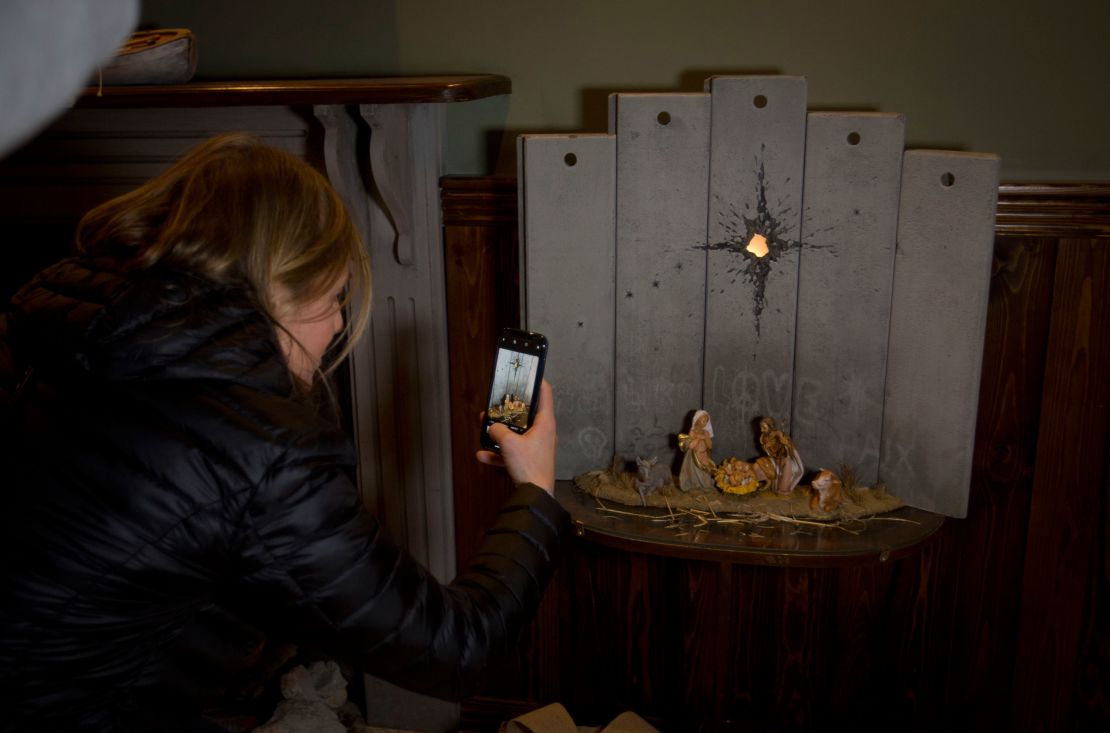 A visitor takes pictures of a new artwork dubbed "Scar of Bethlehem" by the artist Banksy.