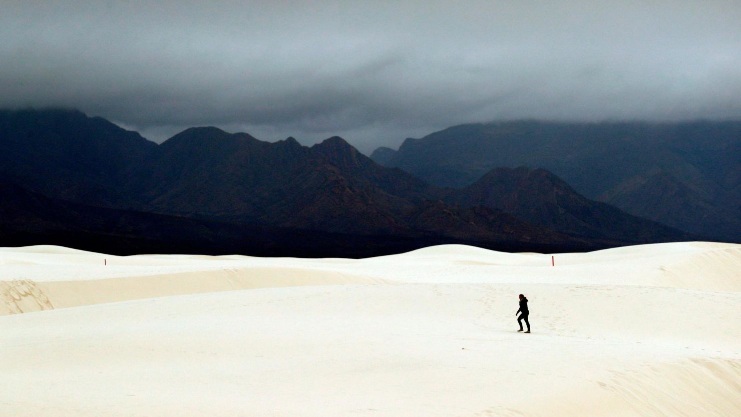 A visitor walks across dunes at White Sands National Monument as a rain storm passes near Alamogordo, New Mexico, on February 10, 2019.