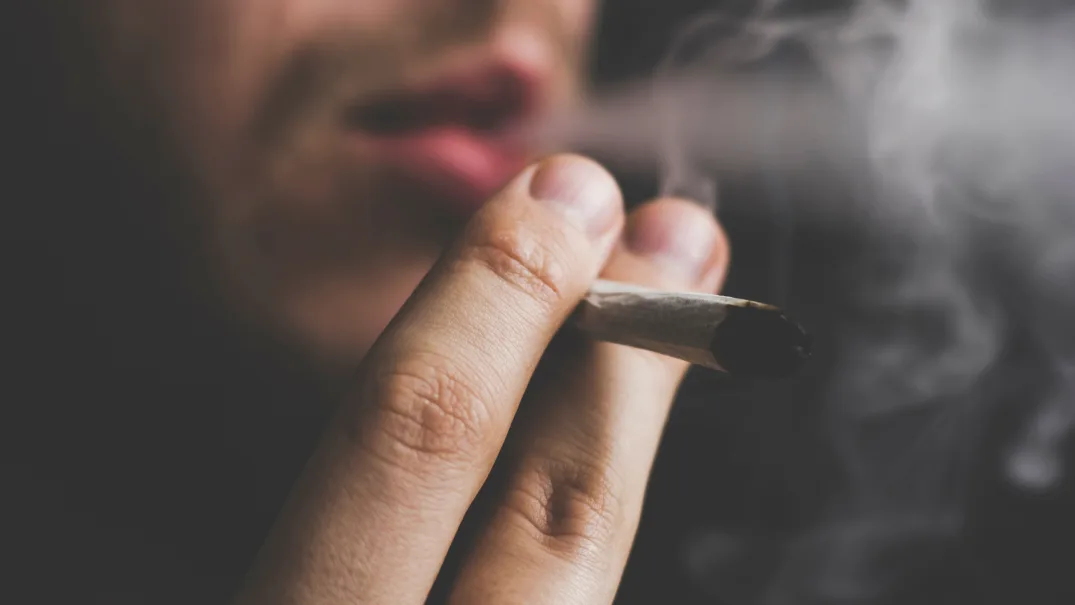 A man smokes a marijuana cigarette. 