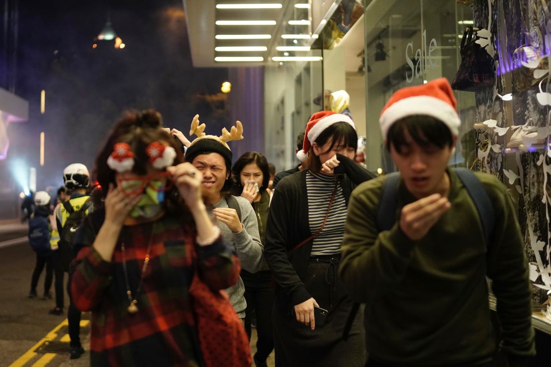 Residents dressed for Christmas festivities react to tear gas as police confront protesters on Christmas Eve in Hong Kong.